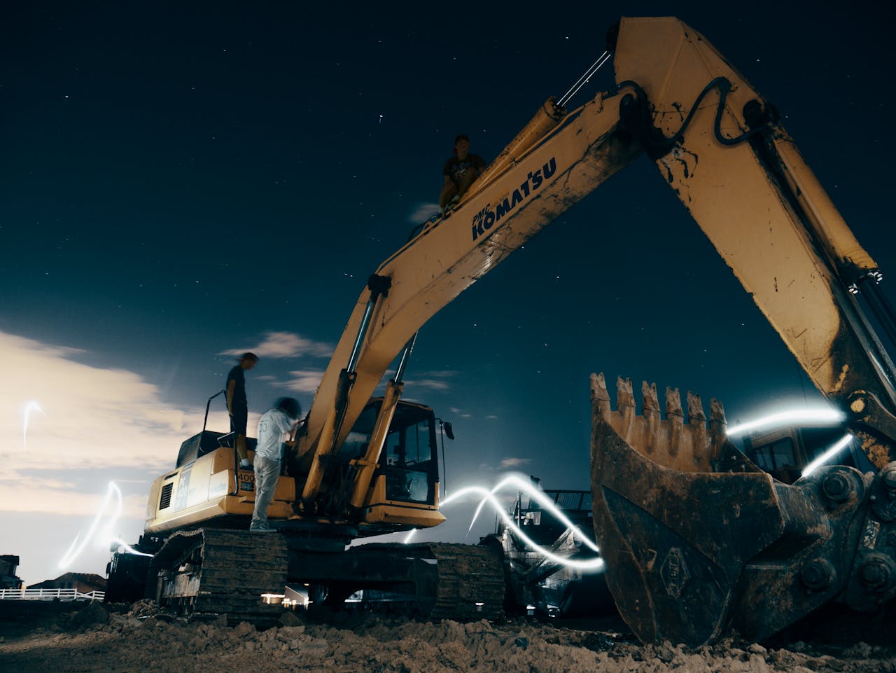 Crafting Captivating Headlines: Your awesome post title goes here A powerful excavator at a construction site under the night sky, with workers around.