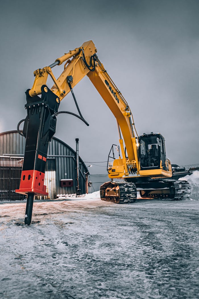 The Art of Drawing Readers In: Your attractive post title goes here A yellow excavator with a hydraulic breaker parked on a snowy construction site.